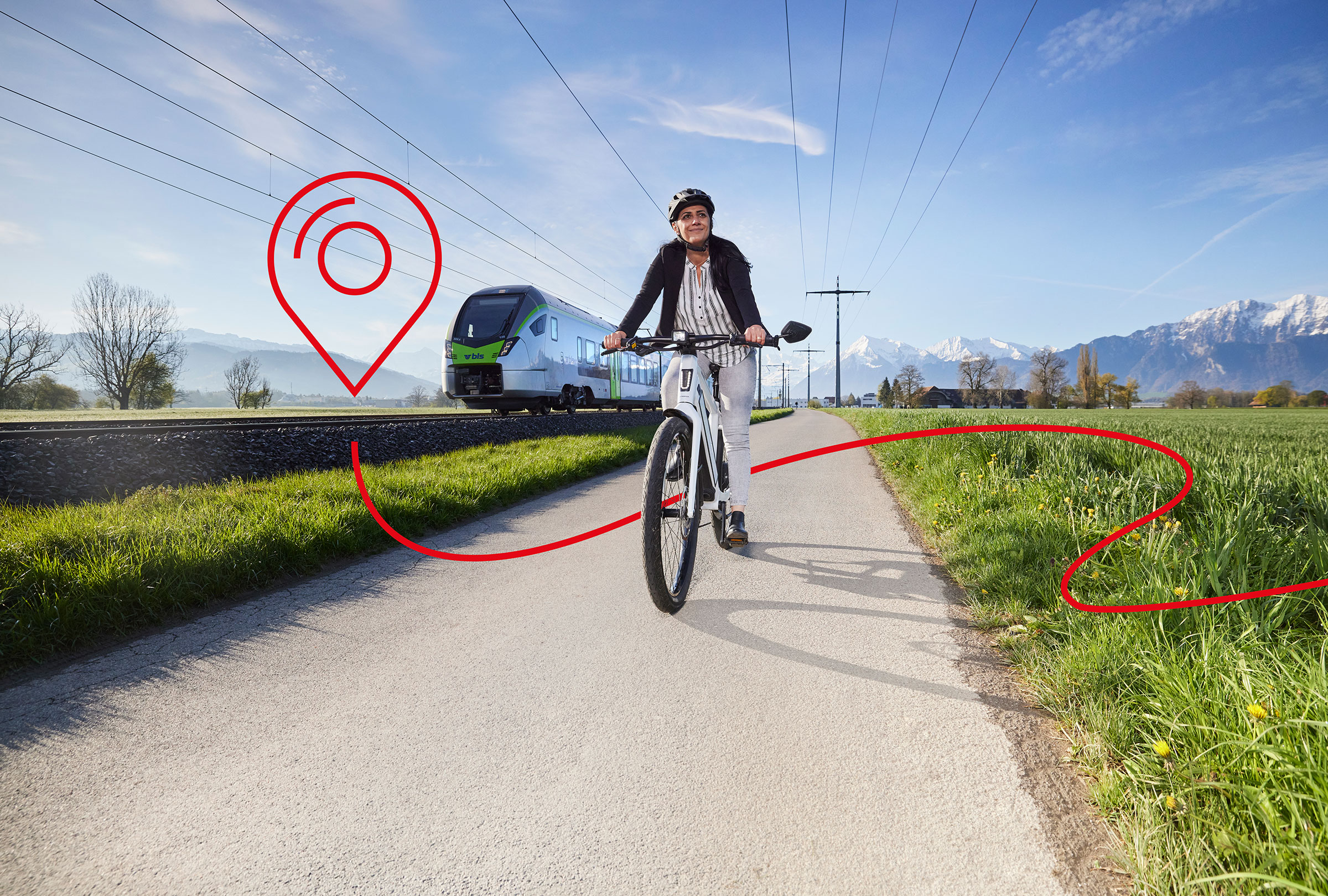 Eine Frau ist auf dem Velo unterwegs. Im Hintergrund ist ein Zug zu sehen.